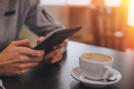 hands with the tablet or the ebook and the coffee mugの写真素材