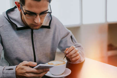 having breakfast or drinking coffee with the mobile phoneの写真素材