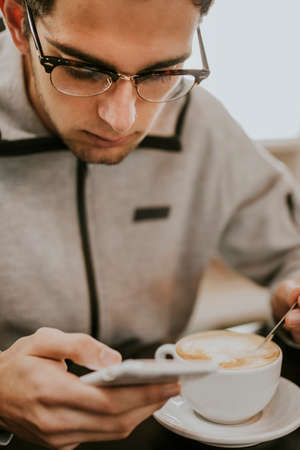 having breakfast or drinking coffee with the mobile phoneの写真素材