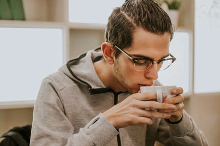 young modern intellectual drinking coffeeの写真素材