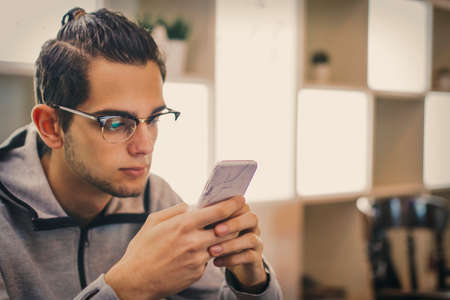 young fashion with mobile phone in the cafeteriaの写真素材