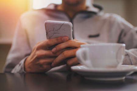 hand closeup with mobile phone and coffee cupの写真素材