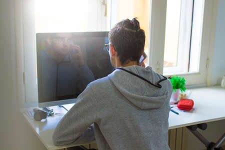 young man talking on the phone at home or at the officeの写真素材