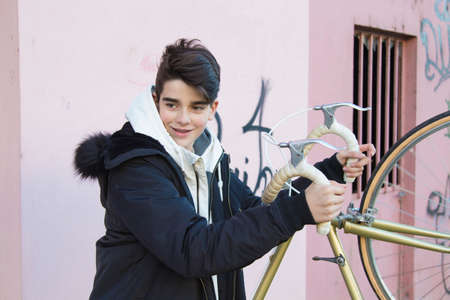 young teenager with vintage bike on city street