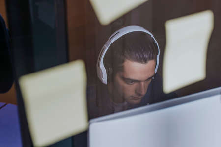 young with headphones in the studio with the computer working or studyingの写真素材