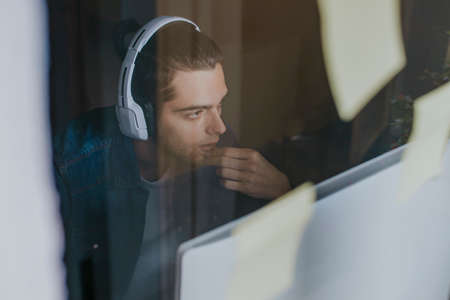 young with headphones in the studio with the computer working or studyingの写真素材