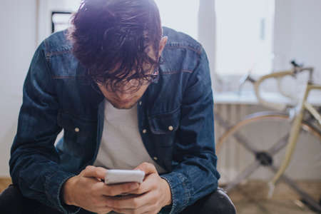 young at home typing in mobile phone