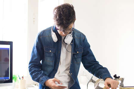 young man watching mobile phone in studio room or officeの写真素材