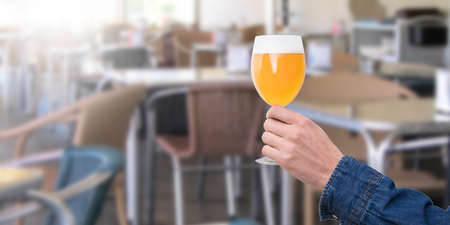 Hand with a glass of beer in the bar or pubの写真素材