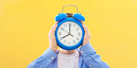 young person with clock or alarm, concept of time and punctualityの写真素材
