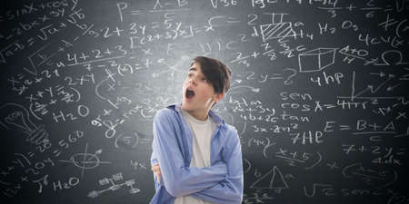 student with surprise and frightened looking at the formulas on the blackboardの写真素材