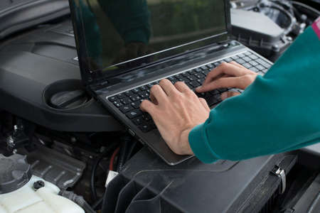hands on the workshop computer checking or fixing the carの写真素材