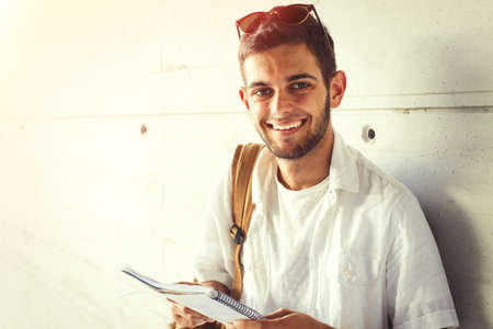 student portrait smiling at the bottom wall with books and backpackの写真素材