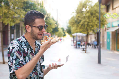 portrait of young eating in the street fast food, pizzaの写真素材