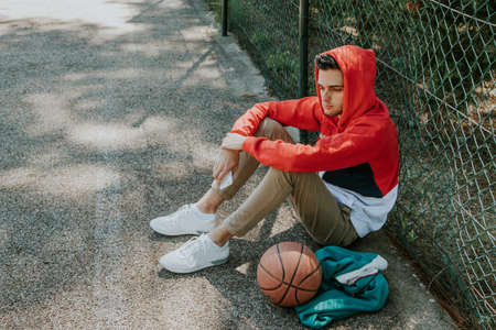 fashionable young man sitting on the basketball court