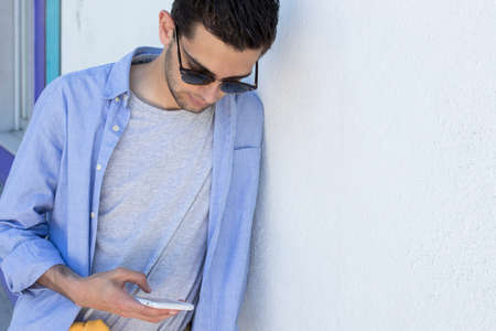 young man with mobile phone on the wallの写真素材