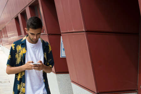 young man with mobile phone walking down the street