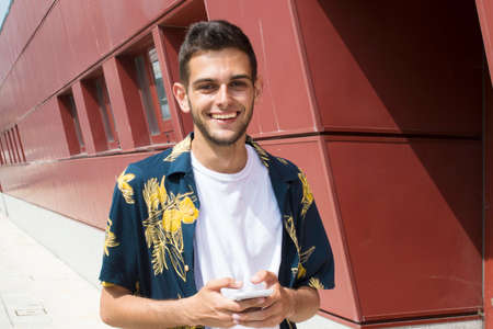 young man with mobile phone walking down the street