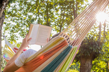 reading at dusk in the hammock with the open bookの写真素材