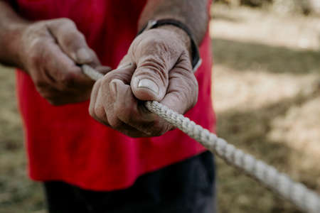 older man's hands pulling the ropeの写真素材