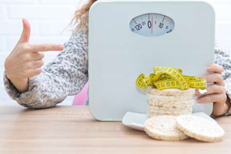 diet and slimming concept, corn cakes with tape measure and girlの写真素材