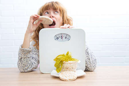 diet and slimming concept, corn cakes with tape measure and girl