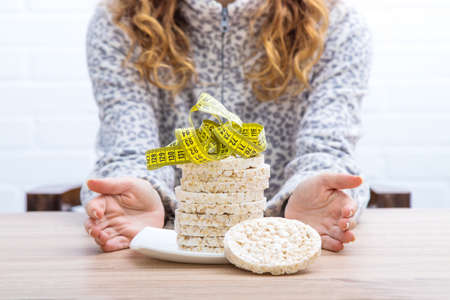 diet and slimming concept, corn cakes with tape measure and girlの写真素材