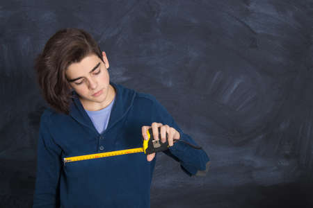 young man with tape measure and expression of doubt