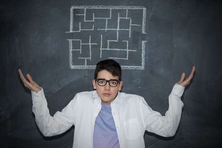 portrait of young man with glasses and labyrinth drawn on the slateの写真素材