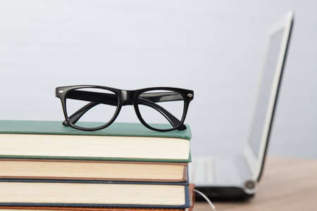glasses on stacked books and laptopの写真素材