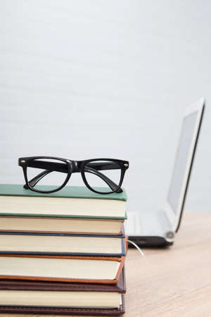 glasses on stacked books and laptopの写真素材