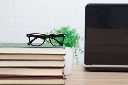 glasses on stacked books and laptopの写真素材