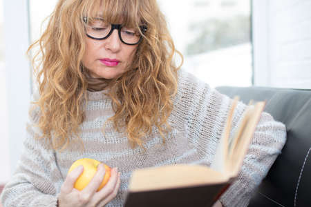 adult woman reading the book on the couch