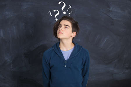 adolescent with slate background and thoughtful question marks