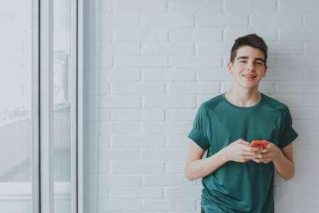 young or teen with mobile phone on the wallの写真素材