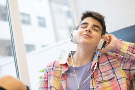 young man listening to music at home with headphones and phone