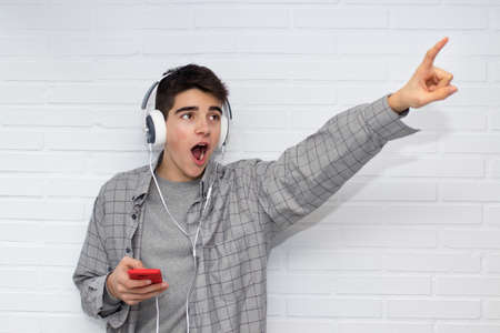 funny young man with mobile phone and earphonesの写真素材