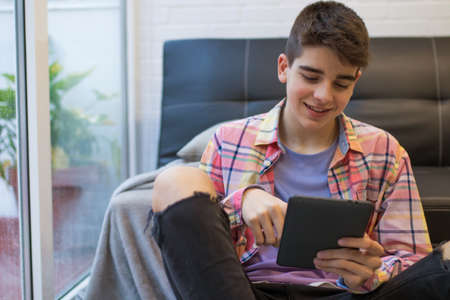 young teenager at home with digital tablet or laptopの写真素材