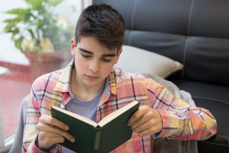 young at home reading a book or studying