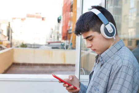young or teen with mobile phone and outdoor earphonesの写真素材