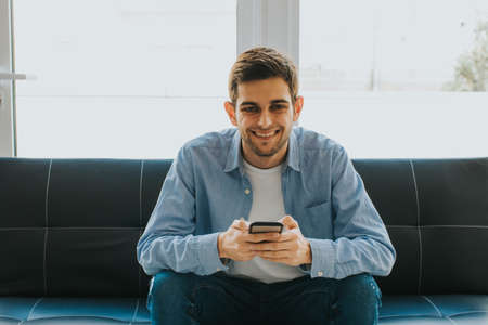 young man or teenager with mobile phone indoorsの写真素材