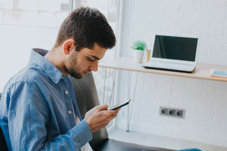 young man or teenager with mobile phone indoors
