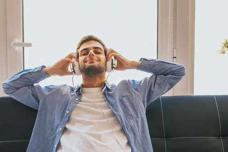 young man listening to music at home with headphonesの写真素材