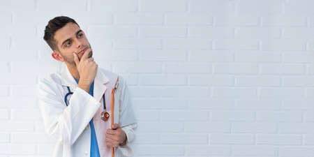 doctor thinking about white brick backgroundの写真素材