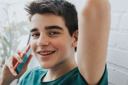 portrait of a male teenager with braces and mobile phoneの写真素材