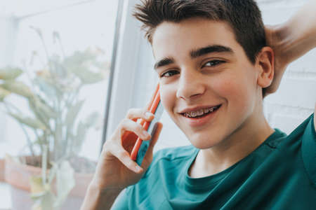portrait of a male teenager with braces and mobile phoneの写真素材