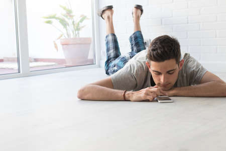 young man with mobile phone at homeの写真素材