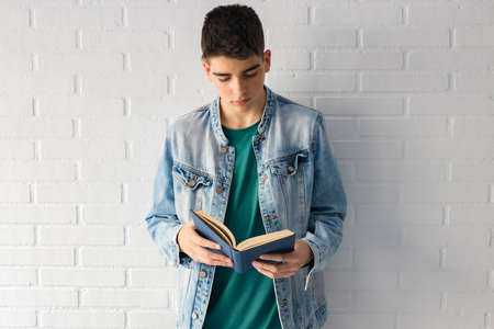 young teenager or fashion student with books supported on the wall