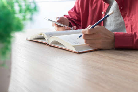 hand with the pencil writing in the book or notepad