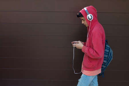 young man or student with mobile phone and headphones outdoorsの写真素材